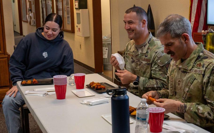 U.S. Air Force Staff Sgt. Isabelle Velker, left, 18th Munitions Squadron munitions inspector, Chief Master Sgt. Brandon Wolfgang, 18th Wing command chief and Chief Master Sgt. James Toombs, 18th Maintenance Group senior enlisted leader, eat hot wings during an Airman development day at Kadena Air Base.
